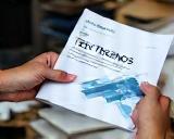 Hands holding a report labeled 'Tech Trends'